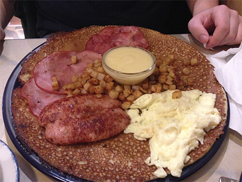 The Boar's (Farmer's) Pannekoek - two eggs, bratwurst, slices of DeBakon and Ham, served with hash browns and Hollandaise Sauce on top of a Dutch Pannekoek.