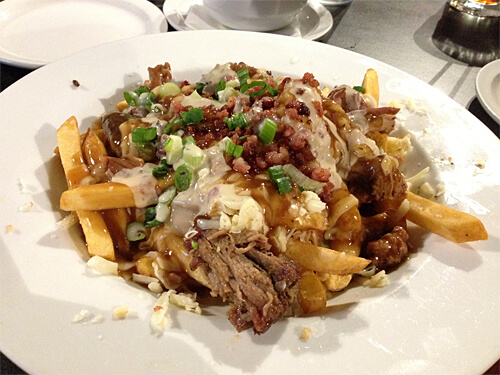 Give Me The Hogg Slopp at Sloppy Hoggs Roed Hus - fries topped with pulled pork, gravy, smoke house aged cheddar, green onions, bacon crumble and waffle sauce. ($7.75)
