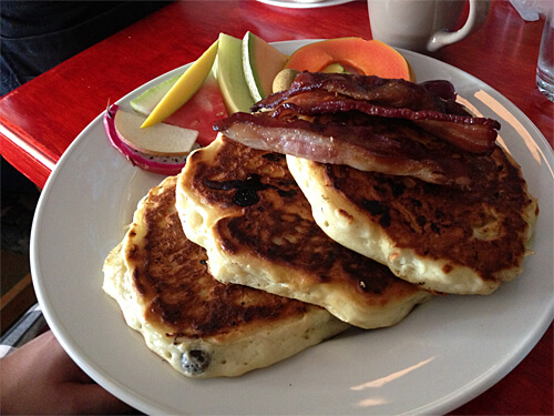 Blueberry Yogurt Pancakes - big, light, fluffy blueberry pancakes with butter, maple syrup, fresh fruit and bacon. ($15)