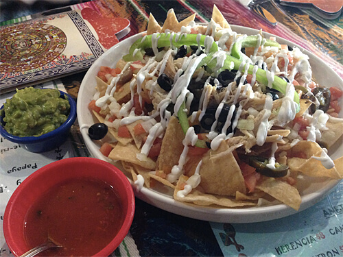 Amigos Nachos - freshly made crispy tortilla chips covered with mozza, tomatoes, onions, jalapenos, olives & peppers, with sour cream and salsa. $12.99